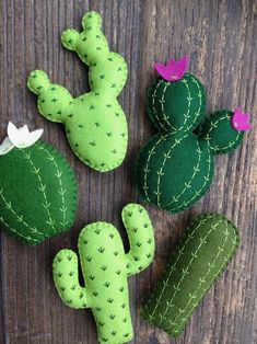 three felt cactus plants sitting on top of a wooden table