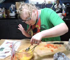 a woman in glasses is making food on a cutting board