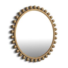 a round mirror with balls on the rim and an oval frame, hanging on a wall