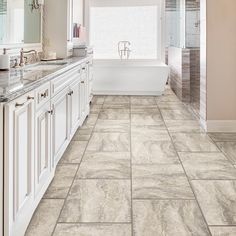 a large bathroom with white cabinets and marble tile flooring, along with a walk in shower