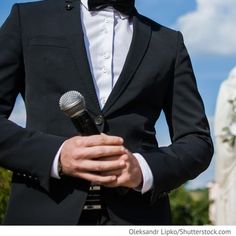 a man in a tuxedo holding a microphone