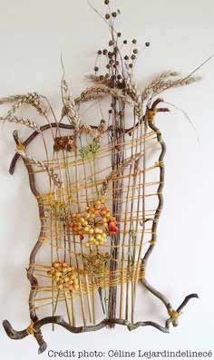 a sculpture made out of branches and twigs with berries on them, sitting against a white wall