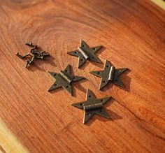 five small metal stars on a wooden surface