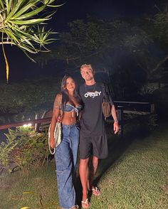 a man and woman standing next to each other in front of a tree at night