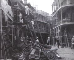 an old black and white photo of men on scaffolding