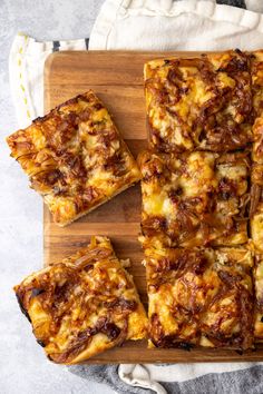 square slices of pizza sitting on top of a wooden cutting board