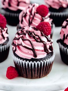 cupcakes with raspberries and chocolate frosting on a white platter