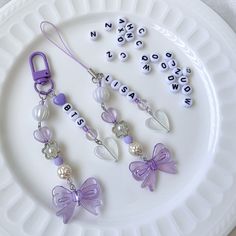 a white plate topped with purple and white beads next to keychains on top of each other