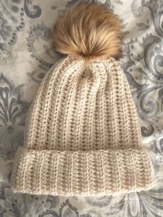 a white knitted hat with a brown pom - pom sitting on top of it