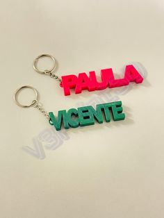 two plastic key chains with the word paula and vicente printed on them, sitting next to each other