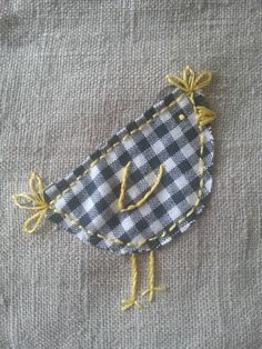 an embroidered bird sitting on top of a piece of cloth