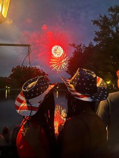 two people wearing patriotic hats looking at fireworks