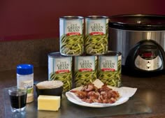 several cans of green beans are on the counter next to an instant pot and some other ingredients