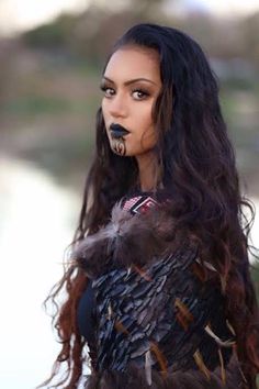 a woman with black makeup and feathers on her face is standing in front of the camera