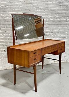 a wooden desk with a mirror on top of it and a brick wall in the background