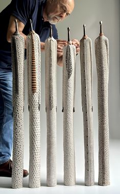 a man is looking at some type of sculpture made out of yarn and metal rods