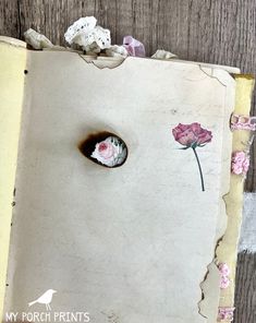 an open book with flowers on it and torn paper around the pages that have holes in them