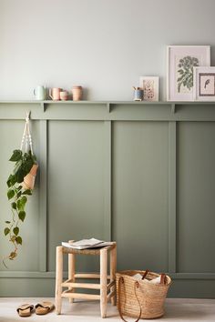 a wooden stool sitting next to a green wall