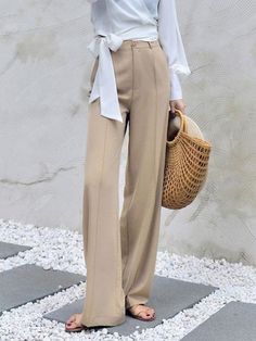 a woman standing in front of a white wall holding a basket and talking on a cell phone