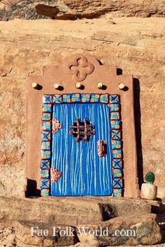 a blue door in the side of a stone wall with decorative decorations on it's sides