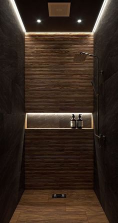 a modern bathroom with dark wood walls and lighting on the ceiling is lit by recessed lights