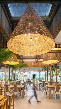 the interior of a restaurant with wooden tables and chairs, hanging wicker lamps and plants