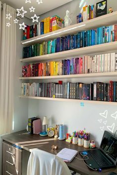 a laptop computer sitting on top of a desk in front of a book shelf filled with books