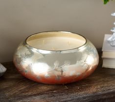 a metal bowl sitting on top of a wooden table next to a white flower vase