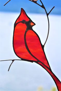 a stained glass cardinal sitting on a branch with two small birds perched on it's back