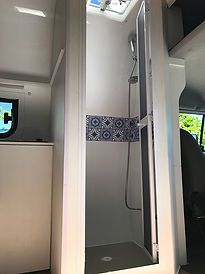 the inside of a small bathroom with a shower and television in it's corner