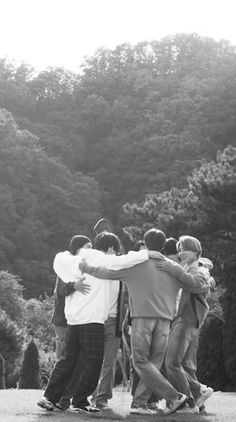 a group of young men standing next to each other on top of a field with trees in the background