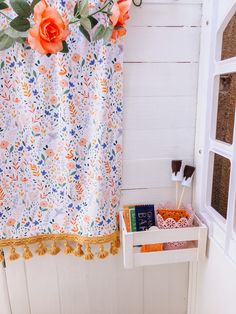 an orange rose hangs on the shower curtain next to a shelf with soaps and toothbrushes