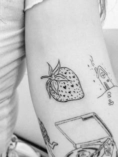 a woman's arm with tattoos on it and an image of a strawberry in a box