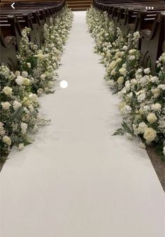 the aisle is decorated with white flowers and greenery