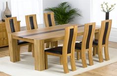 a wooden table with black leather chairs and a plant in the corner next to it