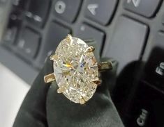 an oval diamond ring sitting on top of a computer keyboard