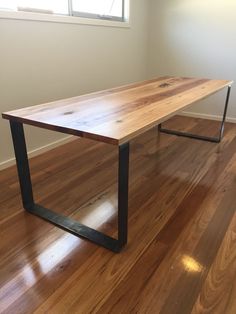 a wooden table sitting on top of a hard wood floor next to an open window