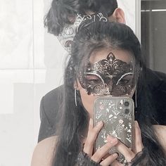 a woman wearing a mask and holding a cell phone in front of her face