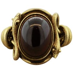 A sweet and chic ring designed in the Egyptian Revival style. It features a luscious cabochon red garnet weighing approximately 10 carats. It is set in 18k yellow gold with gold snakes coiling and wrapping around the two sides of the ring. A unique and one of a kind work of art. Ring Size 7 Chic Rings, Art Ring, Garnet And Gold, Snake Jewelry, Egyptian Revival, Snake Ring, Gold Snake, Red Garnet, Cocktail Ring