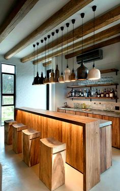 a bar with stools and lights hanging from the ceiling in a large open room