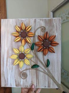 a person holding up a piece of art made out of wood with flowers on it