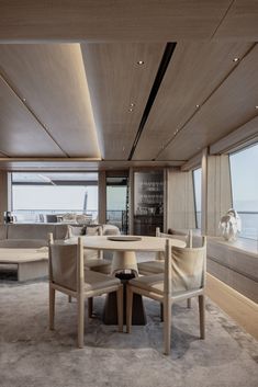 the interior of a boat with wooden furniture and large windows looking out on the water