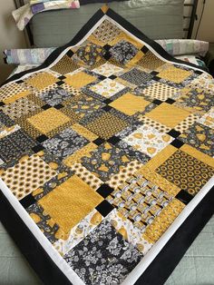 a black and yellow patchwork quilt on a bed