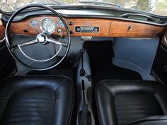 the interior of an old fashioned car with black leather seats and wood trimmings