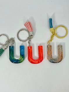 the word u is made up of three different colors and shapes, with one keychain attached to it