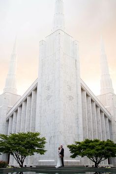 a bride and groom standing in front of the mormon temple