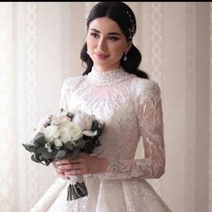 a woman in a white dress holding a bouquet of flowers and wearing a tiara