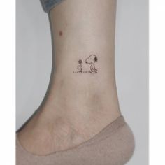 a small tattoo on the ankle of a woman's foot with a dog and cat