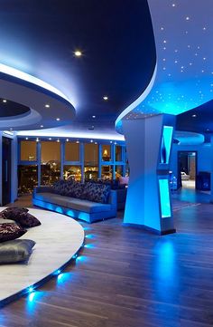 an image of a room with blue lighting on the ceiling and couches in it