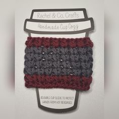 the crocheted coffee cup cozy is made with red, gray and black yarn